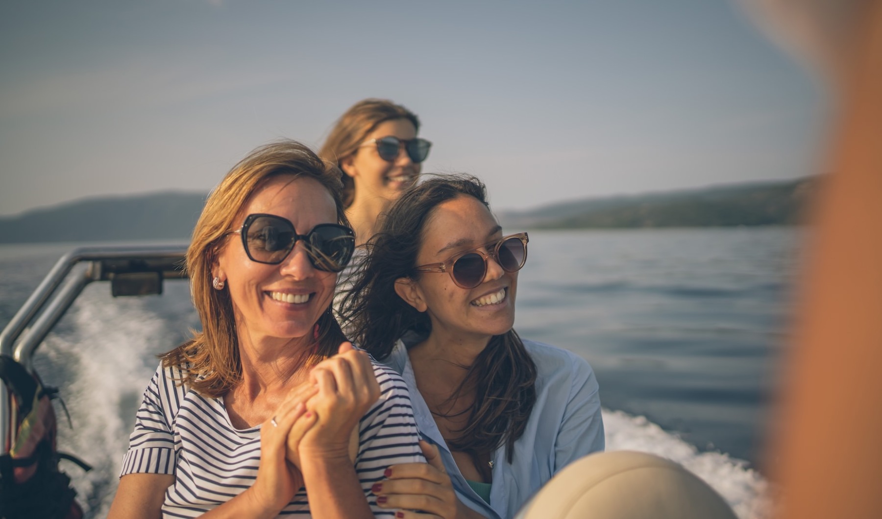 Live at the center of it all A group of women hugging on a boat