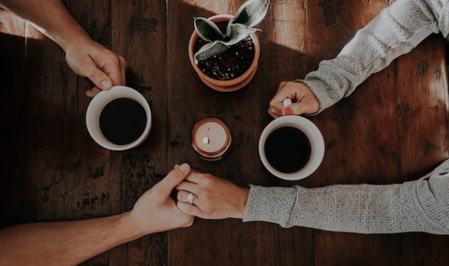 Everything In Reach Couple holding holding hands while drinking coffee